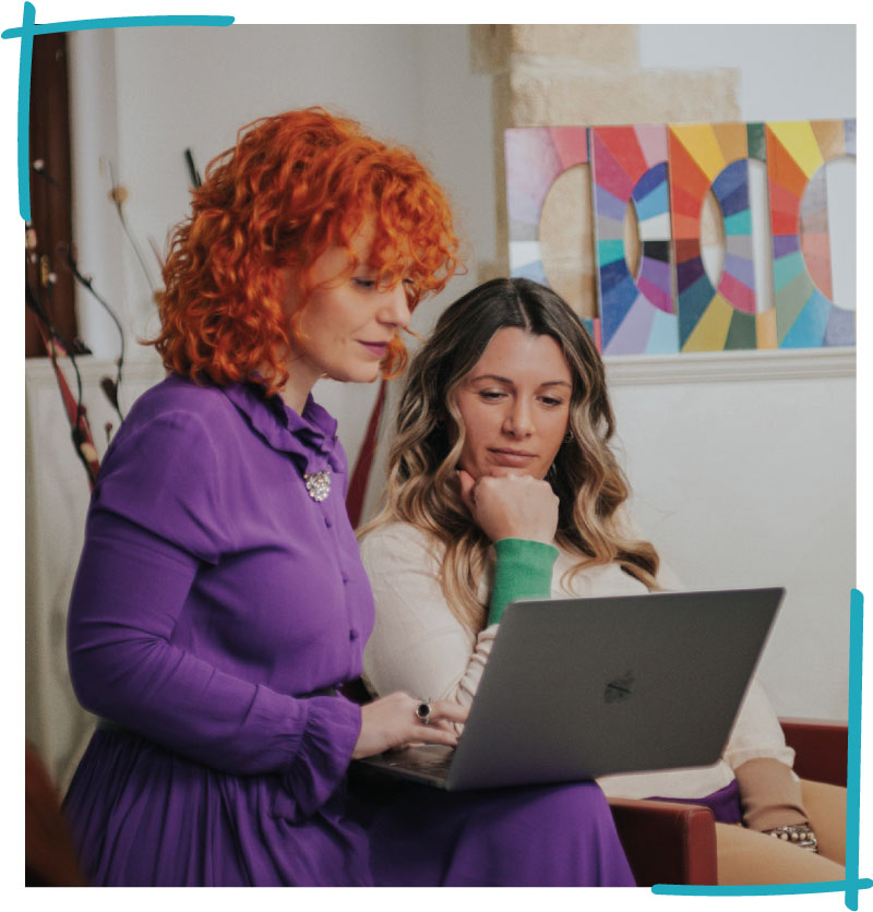 Bruna Viola the hair colorist showing something to her client with her MacBook laptop
